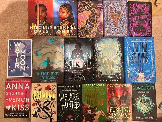 Image of 3 rows of books (5,5,6 - 16 books total) layed out on a beige carpet